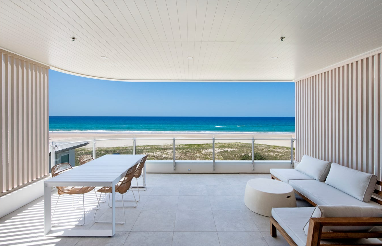 Oceanfront balcony with outdoor dining and lounge overlooking the beach