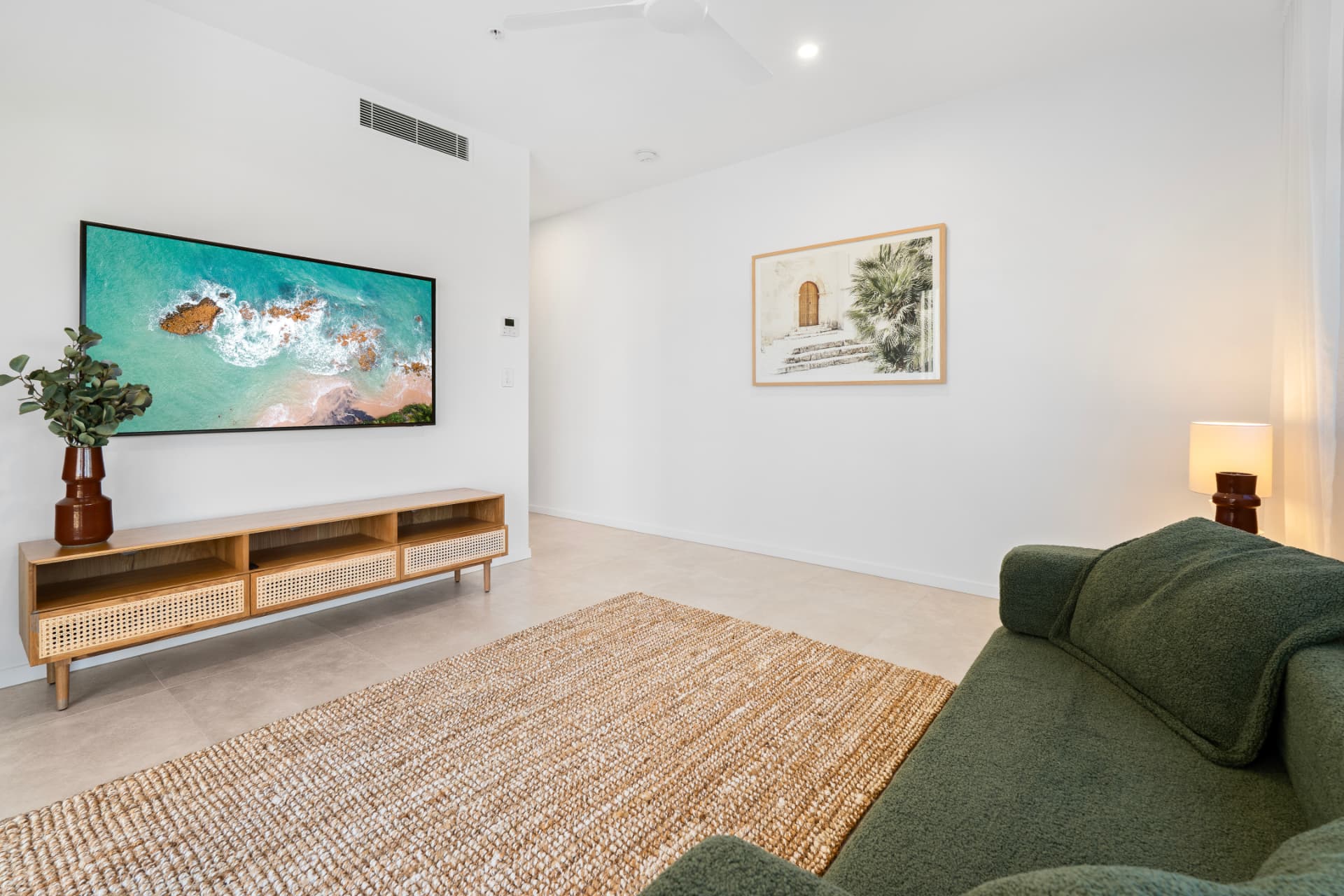 Media lounge with boucle sofa, jute rug and coastal artwork