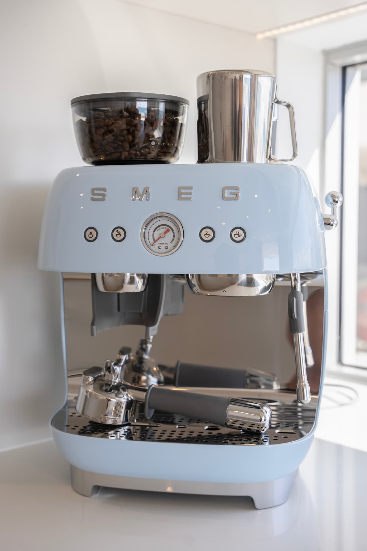 Pastel blue espresso machine with freshly ground beans on the kitchen bench