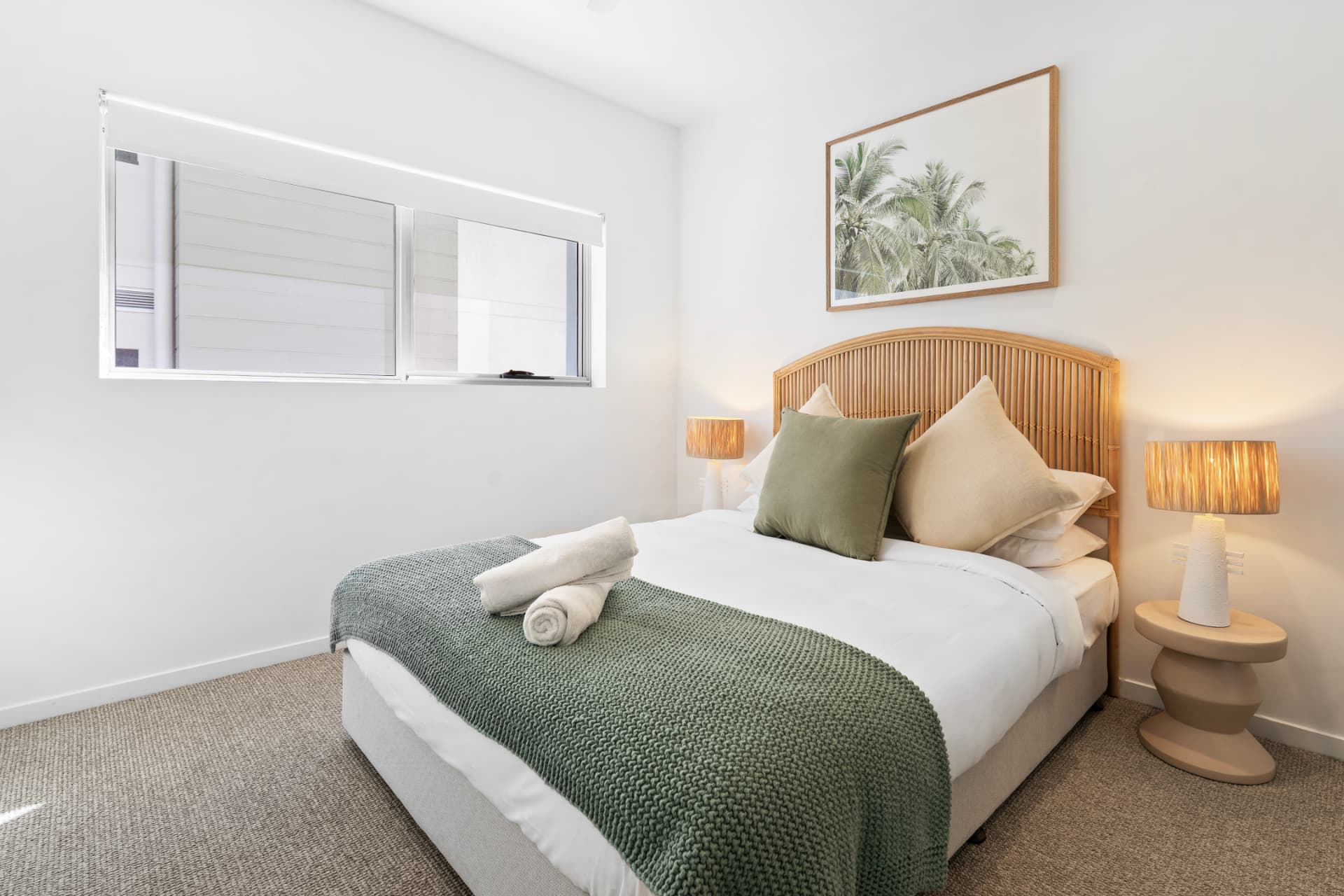 Guest bedroom with rattan bedhead and warm bedside lighting