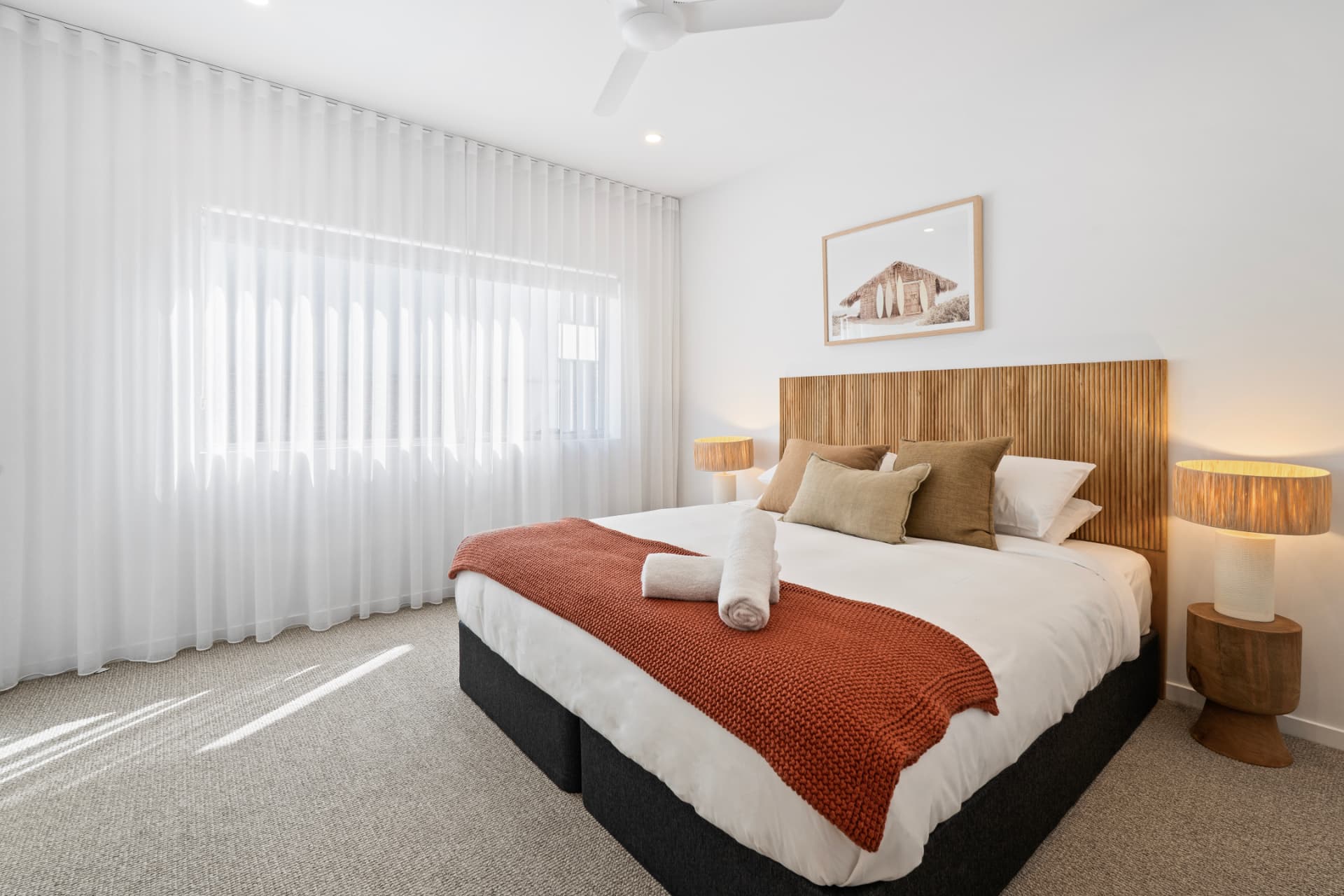 King bedroom with timber slat headboard and soft sheer curtains