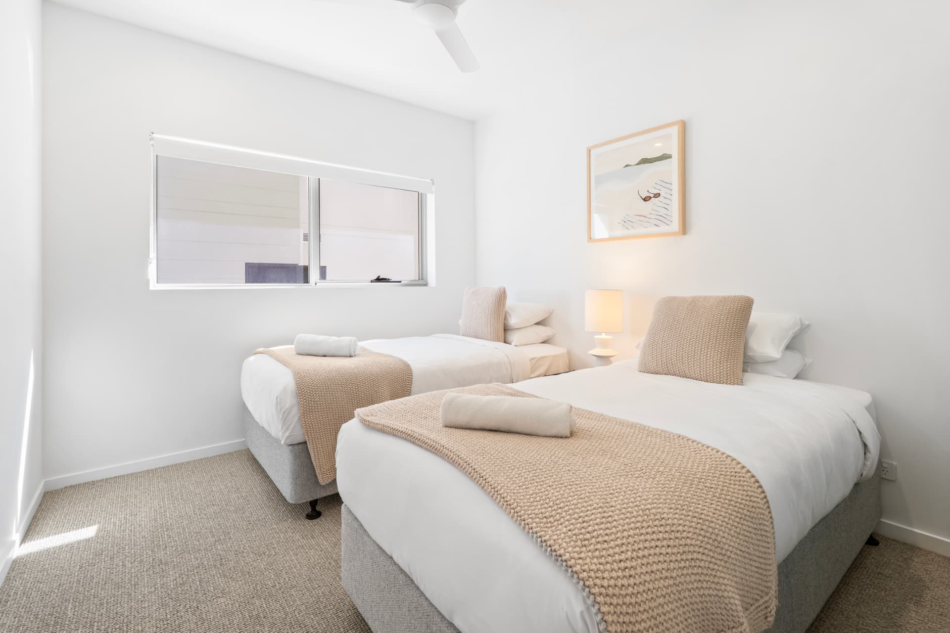 Twin bedroom dressed in white linen with knitted throws
